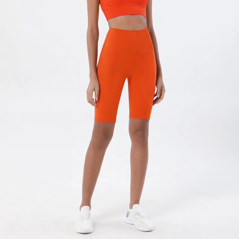 Model wearing orange women’s breathable high-waist cycling shorts, tummy control biker shorts