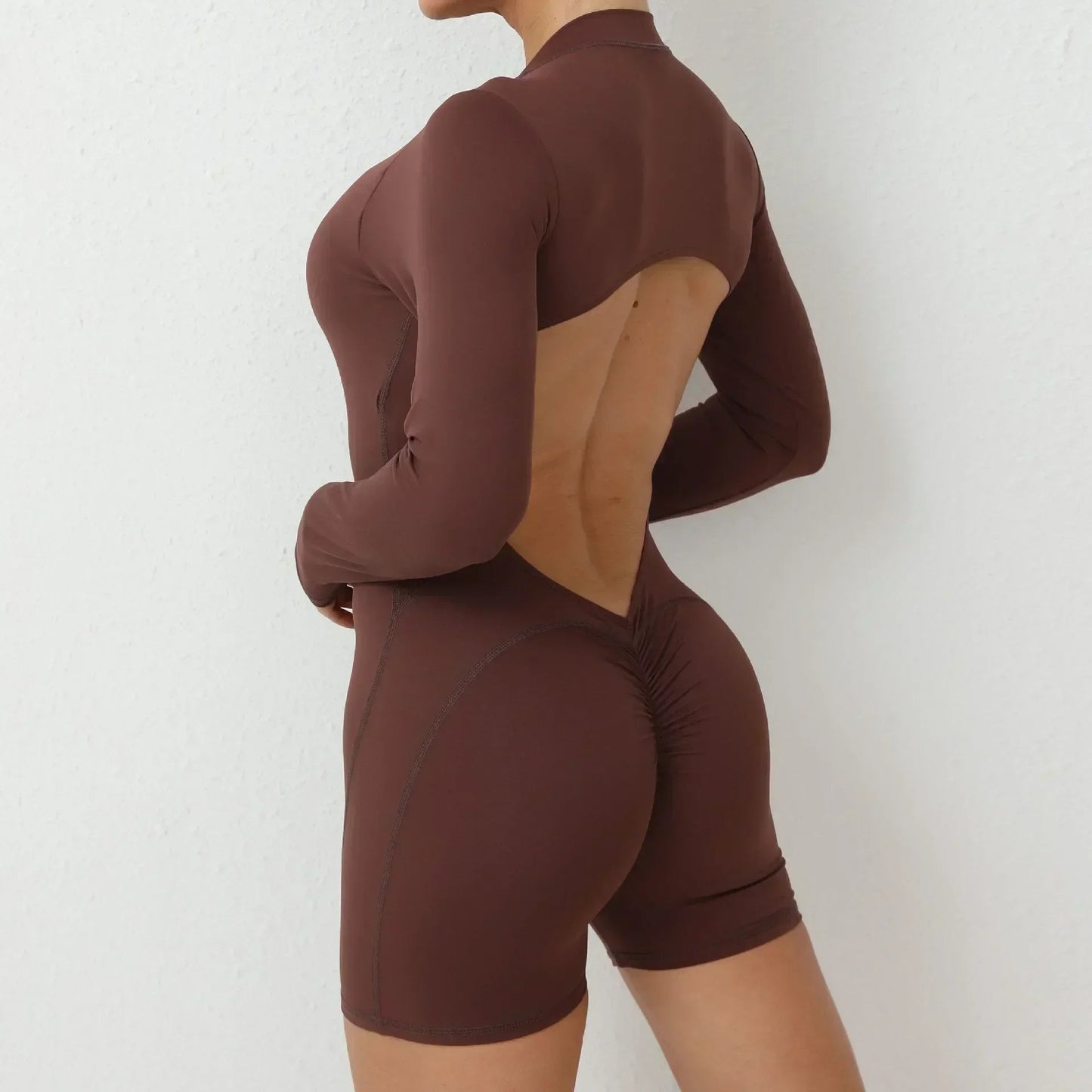 Model wearing brown women’s open back workout jumpsuit, seamless V-back one-piece