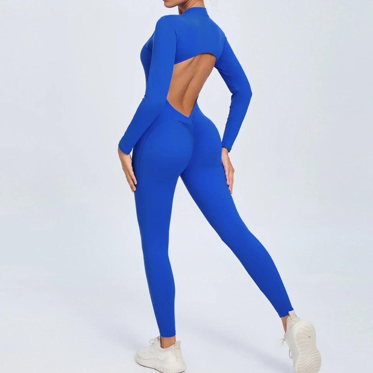 Model wearing blue women’s open back workout jumpsuit, seamless V-back one-piece - long