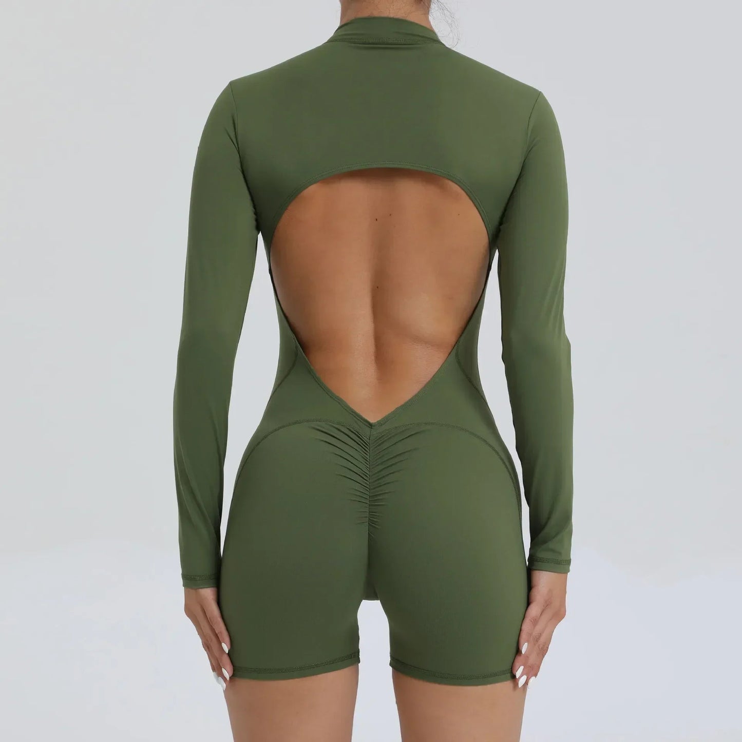 Model wearing green women’s open back workout jumpsuit, seamless V-back one-piece