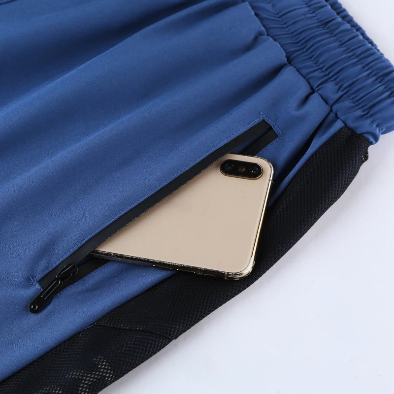 Phone displaced inside of zipper pocket of a blue Patchwork Running Shorts Zip Pockets