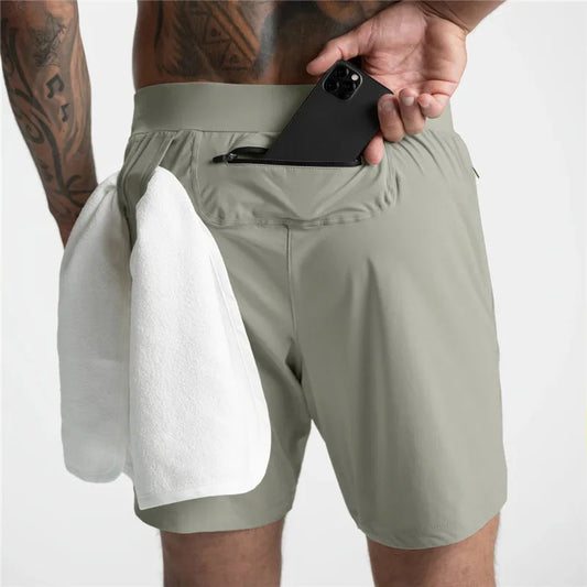 Man modeling the back view of light green Men's Trail Running Shorts, placing a cell phone in the back zipper pocket with a towel hanging through the towel loop.