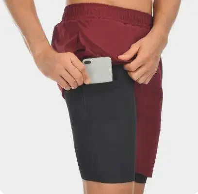 Model wearing maroon red men’s 2-in-1 running shorts with compression liner